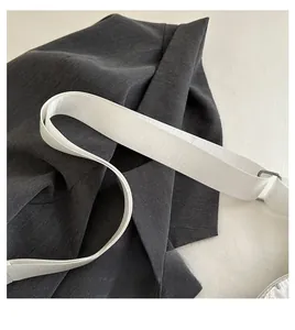 Close-up of white woven shoulder strap with silver metal buckle on a crescent bag