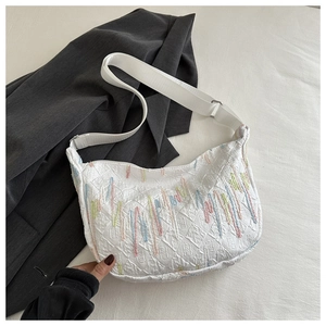 Detail of white quilted half-moon bag with colorful wave embroidery and wide strap
