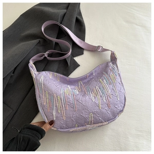 Detailed view of purple baguette bag featuring embossed monogram and wavy embroidery lines