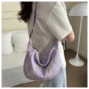 Detail of a purple pleated hobo bag featuring colorful wavy embroidery on wide strap