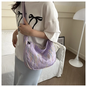 Detailed view of a purple crescent shoulder bag with embroidery and adjustable strap