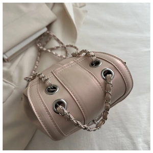 Dettaglio della borsa a secchiello rosa chiaro con occhielli in metallo e catena