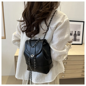Detail of black vintage bucket backpack with metal chain straps and twist lock closure