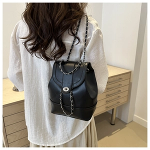 Détail d'un sac à dos noir en cuir avec fermoir rotatif argenté et bandoulière en chaîne