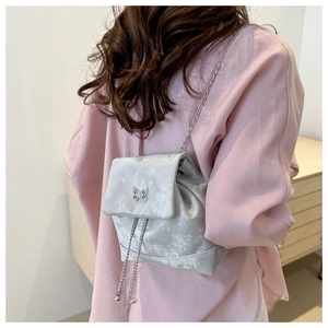 Detail of silver velvet mini backpack with metallic butterfly clasp and chain strap