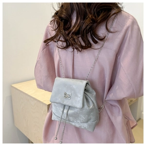 Detail of silver velvet mini backpack with metal butterfly buckle and chain straps