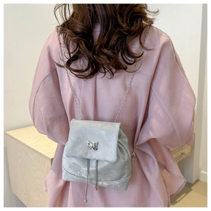 Detalle de la mochila de terciopelo plateado con hebilla de mariposa y cadenas