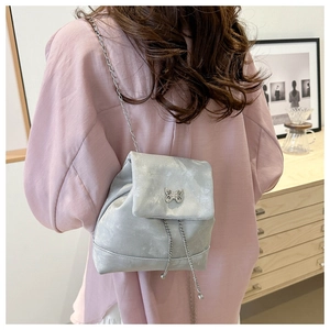 Detalle de mochila plateada metalizada con hebilla de mariposa y correa de cadena en modelo
