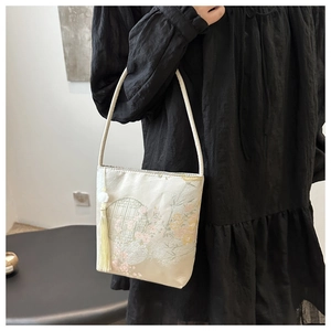 Details der eleganten beigen Seiden-Beuteltasche mit Blumenstickerei und Quaste