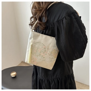 Detail einer eleganten chinesischen Eimertasche mit Bestickung, gelben Quasten und Jade-Anhänger