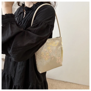 Detail der bestickten goldenen Beuteltasche mit Phönixmuster und edlen Seidenquasten