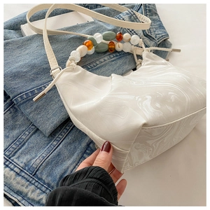Detail of white marble print handbag with colorful beaded handle and shoulder strap