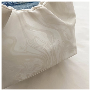 Detailed macro view of the pleated beige cloud bag with marble texture and denim lining