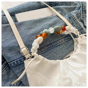 Detail of white bucket bag with marble texture and colorful beaded handle with silver buckle