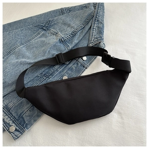 Detail der minimalistischen schwarzen Nylon-Umhängetasche mit Schnalle auf blauem Denim