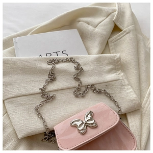 Detailed close-up of pink patent leather mini bag featuring silver butterfly buckle