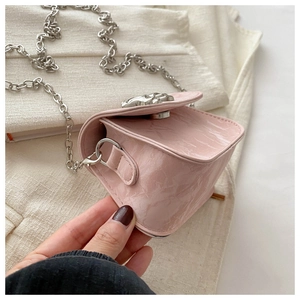Detail of pink mini bag with wrinkled leather texture and silver hollowed-out metal clasp