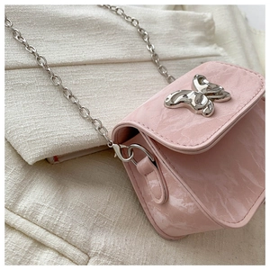 Close-up of pink mini crossbody bag with silver butterfly clasp and chain strap
