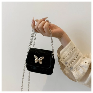 Detail of a mini black velvet crossbody bag featuring a silver 3D butterfly and chain
