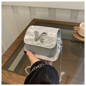 Detailed view of mini silver chain bag with metallic texture and butterfly ornament