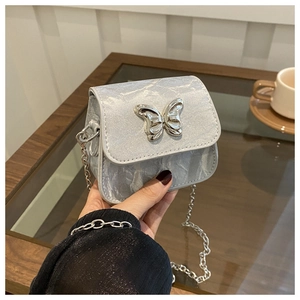Detail of a mini chain bag with metallic butterfly clasp and pleated texture finish