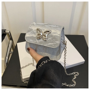 Detailed close-up of a silver mini bag featuring a butterfly buckle and metal chain strap