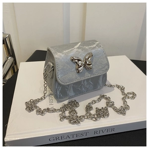 Detail of silver mini crossbody bag featuring a butterfly buckle and metal chain strap
