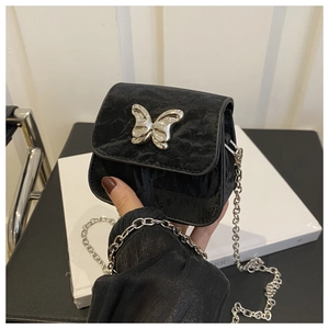 Close-up of a mini black crossbody bag with silver butterfly charm and chain strap