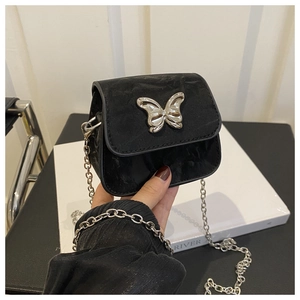 Detailed shot of black mini crossbody bag with silver butterfly buckle and fine chain strap