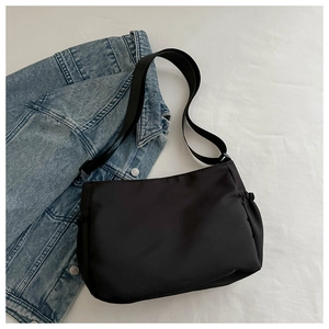 Détail d'un sac bandoulière en nylon noir avec poche latérale à cordon et large bandoulière