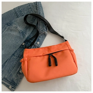 Vue détaillée d'un sac fourre-tout orange en nylon imperméable avec fermeture en corde noire