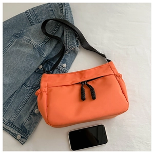 Détail du sac bandoulière orange vif avec tirettes de fermeture éclair tissées noires