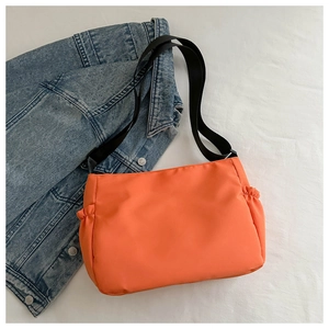 Détail d'un sac bandoulière orange vif en nylon avec poches latérales à cordon et sangle noire