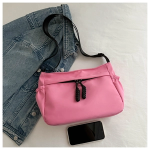Détail du sac bandoulière en nylon rose avec sangle noire et poche zippée