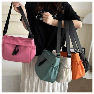 Détail de sacs bandoulière en nylon multicolores avec poches à cordon et larges bretelles