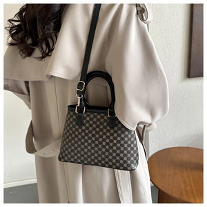 Modische Vintage-Umhängetasche mit Muster, getragen über einem beigen Trenchcoat