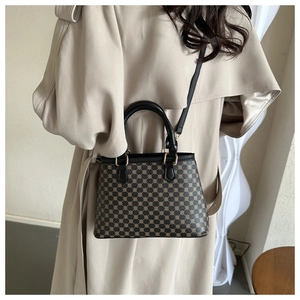 Detail der Vintage-Tasche mit braunem geometrischem Muster und schwarzen Lederriemen