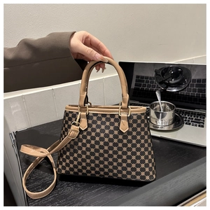 Nahaufnahme der Vintage-Tasche mit geometrischem Muster, Ledergriffen und Goldbeschlägen