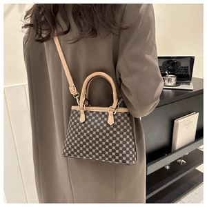 Vintage-Tragetasche mit Monogramm-Muster und cremefarbenen Griffen im Lifestyle-Ambiente