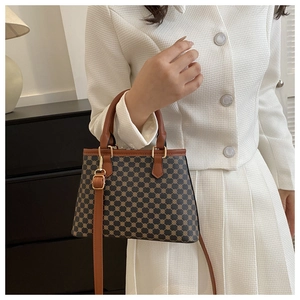 Detail der Vintage-Tasche mit geometrischem Monogramm-Muster und braunem Ledergriff
