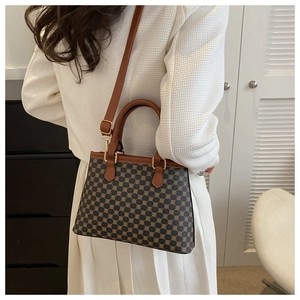 Nahaufnahme einer Vintage-Monogramm-Tasche mit braunen Ledergriffen und Goldbeschlägen
