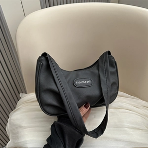 Minimalist black crescent shoulder bag in matte leather featuring a metal logo plate