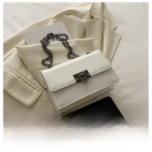 Detailed close-up of a white leather crossbody bag with metal chain and stud buckle