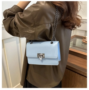 Side view of sky blue crossbody bag with silver chain strap and rivet lock on model