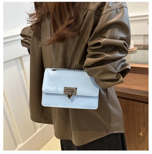 Detail of light blue crossbody bag with silver chain strap and studded metal clasp