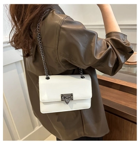 Detail of white leather crossbody bag with vintage silver metal chain and geometric clasp