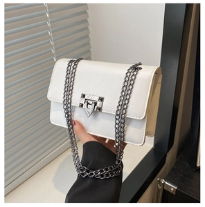 Detail of white leather crossbody bag with silver chain straps and rivet clasp detail