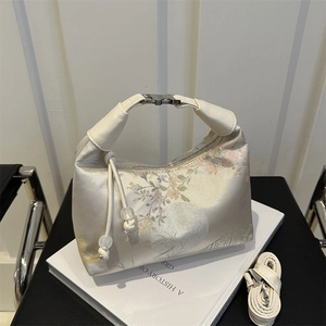 Elegant New Chinese Style handbag with floral brocade and leather handle on a white book