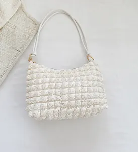 Macro view of white popcorn texture fabric with dual shoulder straps and golden hardware
