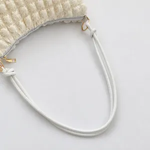 Close-up of beige pleated shoulder bag featuring bubble texture fabric and metal zipper